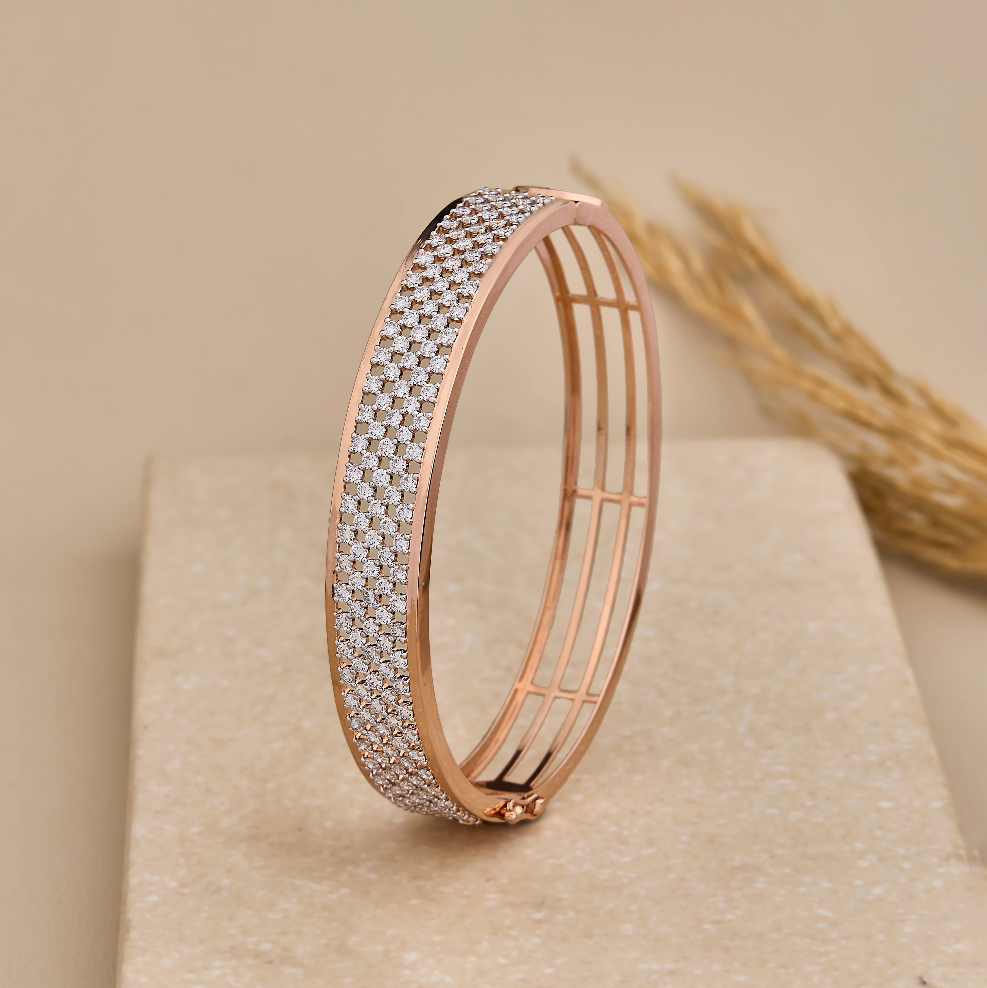Slim silver and rose finish bangles resting on an ivory pebble